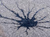 Dunkle Kleksstruktur in milchiger Eisdecke im Moorsee